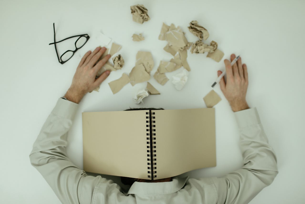 Man resting his head on a desk, appearing drained and disengaged from work.
