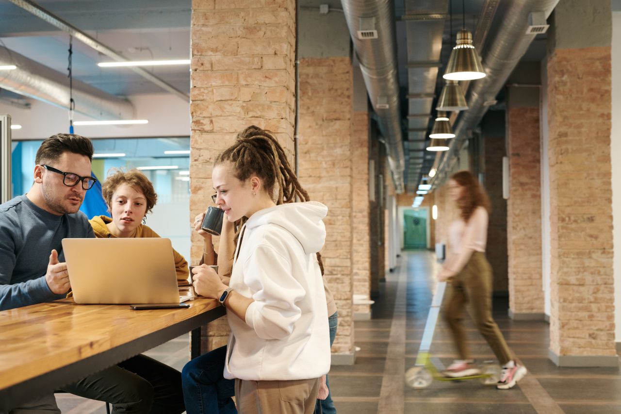 Startup team collaborating and reviewing work on a laptop in a coworking space