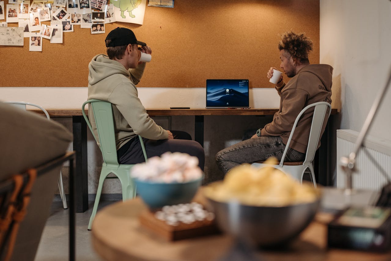 Group of men sitting around a table, illustrating how the 'I'll do it later' mindset spreads and ruins focus and momentum throughout the day.