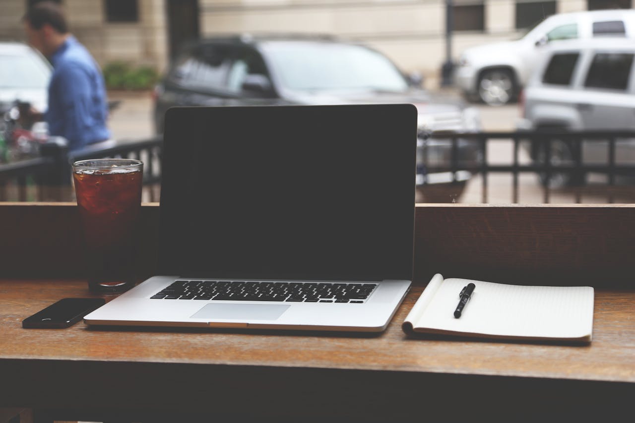 Minimalist workspace with a MacBook and notebook on a wooden table, representing the 80/20 productivity principle of doing less but achieving more.